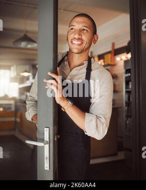 Homme d'affaires heureux regardant l'entrée de son café. Petit propriétaire d'entreprise de course mixte debout dans sa porte de coffeeshop. Un patron de bistro attend les clients Banque D'Images
