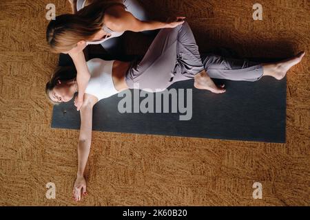 Exercices de yoga. Un entraîneur personnel enseigne à une femme des cours de yoga dans la salle de gym Banque D'Images