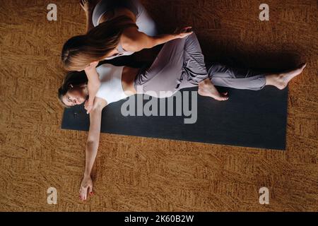 Exercices de yoga. Un entraîneur personnel enseigne à une femme des cours de yoga dans la salle de gym Banque D'Images