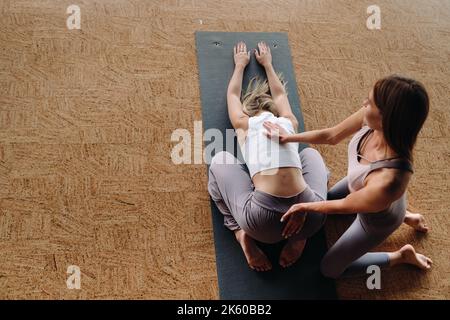 Exercices de yoga. Un entraîneur personnel enseigne à une femme des cours de yoga dans la salle de gym Banque D'Images