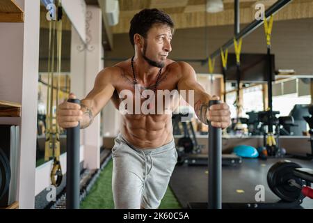 Homme faisant des exercices de traction traînant des poids dans une salle de sport Banque D'Images