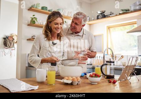 Retraite, couple et cuisine de la nourriture de petit déjeuner avec le sourire heureux dans la cuisine maison du Canada. L'homme et la femme âgés dans le mariage aiment la cuisson du matin Banque D'Images