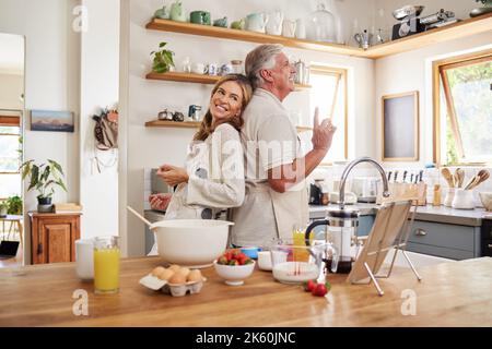 Les couples seniors dansent, cuisinent le petit déjeuner dans la cuisine et aiment faire de la nourriture ensemble pendant la retraite. Les personnes âgées sourient, cuisent ou cuisent Banque D'Images