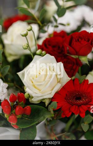 Livraison de fleurs pour tout séjour. Grand bouquet de fleurs rouges et blanches avec brindilles vertes en papier blanc. Gros plan de roses, chrysanthèmes, d Banque D'Images