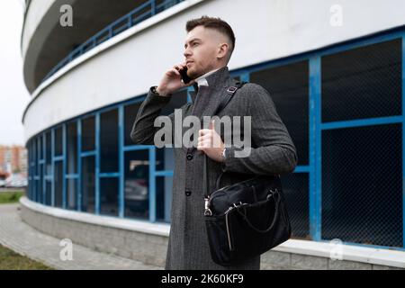 jeune homme d'affaires élégant parle bien au téléphone sur le fond du parking Banque D'Images