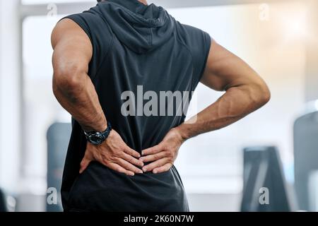 Entraîneur inconnu seul dans la salle de gym et souffrant de blessures au dos. Coach se tenant et se frottant en arrière pendant l'entraînement dans le club de santé d'exercice. Un homme dedans Banque D'Images