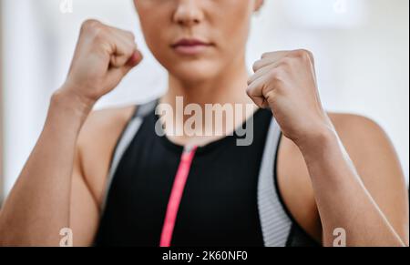 Gros plan d'un entraîneur sérieux inconnu dans la posture de boxe seule dans la salle de gym. Entraîneur caucasien focalisé prêt à se battre en autodéfense dans l'entraînement de club de santé Banque D'Images