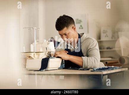 Couture sur mesure ciblée sur une machine. Jeune designer de mode couture d'un morceau de denim. Course mixte à l'aide d'une machine à coudre. Homme d'affaires créatif Banque D'Images