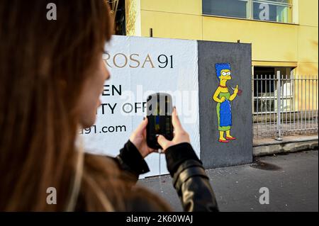 Milan, Italie sur 11 octobre 2022, Une femme prend une photo d'une fresque intitulée "The Cut 2" de l'artiste de rue aleXsandro Palombo représentant le personnage des Simpsons Marge Simpson coupant ses cheveux et donnant le doigt du milieu en solidarité avec les femmes d'Iran devant le consulat iranien à Milan, Italie sur 11 octobre, 2022. Une première version d'une murale similaire, intitulée 'la coupe' est apparue sur 5 octobre au même endroit et a été supprimée plus tard. Credit: Piero Cruciatti/Alay Live News Credit: Piero Cruciatti/Alay Live News Banque D'Images