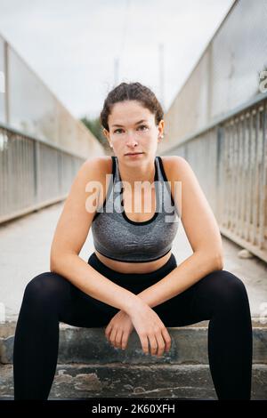 Portrait d'une jeune femme en vêtements de sport sur un pont urbain après l'activité Banque D'Images