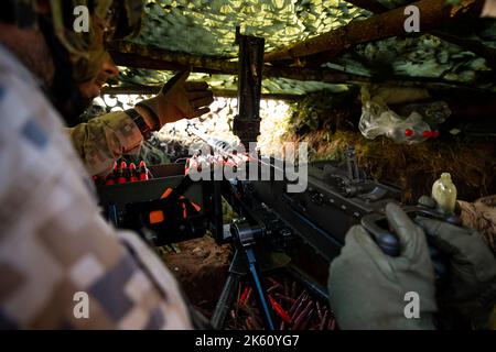 Des soldats en gros plan tirent sur une mitrailleuse 50 Cal machine avec du laiton usé autour d'elle Banque D'Images