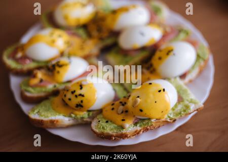 Délicieux œufs benedict au saumon fumé, sauce hollandaise, guacamole et pignons Banque D'Images