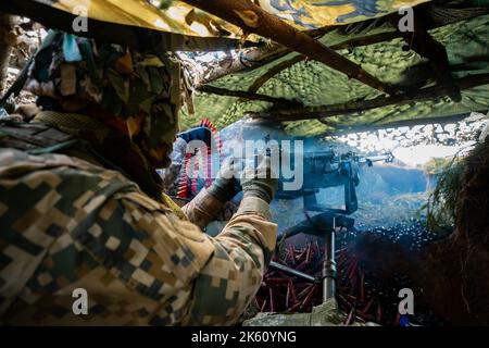 Des soldats en gros plan tirent sur une mitrailleuse 50 Cal machine avec du laiton usé autour d'elle Banque D'Images