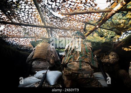 Des soldats en gros plan tirent sur une mitrailleuse 50 Cal machine avec du laiton usé autour d'elle Banque D'Images