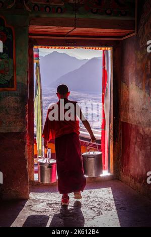 Un jeune moine traversant une porte au monastère de Thiksey, Ladakh, Inde Banque D'Images