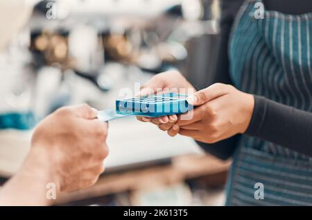 Gros plan d'un employé acceptant un paiement par carte de crédit d'un client dans un café ou un magasin. Mains de la femme utilisant le lecteur de machine à cartes pour traiter sans espèces Banque D'Images