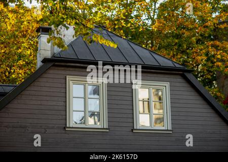 Maison en bois gris avec deux fenêtres blanches et des arbres en arrière-plan Banque D'Images