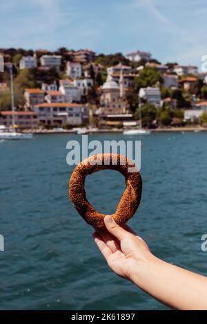 vue rognée de la femme tenant le bagel de sésame turc près de la mer, image de stock Banque D'Images