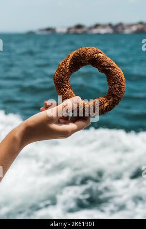 vue rognée d'une jeune femme tenant un bagel de sésame turc près du détroit du bosphore, image de stock Banque D'Images