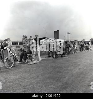 1964, historique, juillet, à l'extérieur dans un domaine sportif à l'hôpital Stoke Mandeville, la maison du Centre national des lésions médullaires, les jeunes en fauteuil roulant pratiquant le tir à l'arc. Un neurochirurgien allemand/britannique, le Dr Ludwig Guttmann, a établi le centre de traitement des blessures à la colonne vertébrale pour l'ex-militaire, et il a ensuite créé les Jeux Stoke Mandeville, précurseur des Jeux paralympiques modernes, dont le premier a eu lieu en 1948, L'année des Jeux Olympiques de Londres et présenté comme son seul sport, le tir à l'arc. Banque D'Images