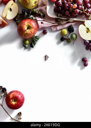 Composition avec fruits frais d'été et baies sur fond blanc. Raisins, prunes et pommes au soleil. Banque D'Images