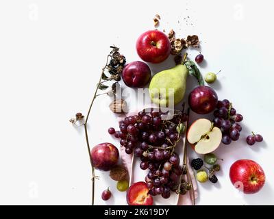 Composition avec fruits frais d'été et baies sur fond blanc. Raisins, prunes et pommes au soleil. Banque D'Images