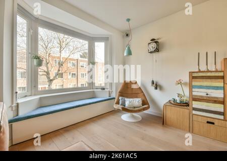 Grande fenêtre dans la chambre meublée avec armoire en bois et chaise sur parquet Banque D'Images