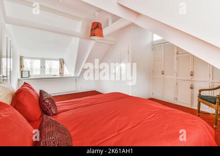 lit simple placé sur moquette rouge dans une chambre moderne avec armoire Banque D'Images