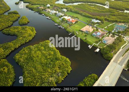 Vue aérienne des banlieues résidentielles avec maisons privées situées près des terres humides sauvages avec végétation verte sur la rive de la mer. Vivre à proximité de la nature Banque D'Images