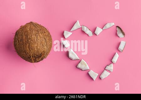Morceaux de noix de coco cassés sur fond rose vif, vue de dessus, espace de copie Banque D'Images
