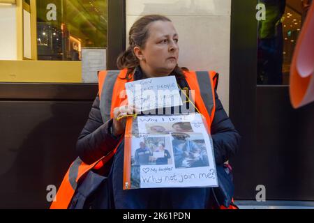 Londres, Royaume-Uni. 11th octobre 2022. Une militante du secteur pétrolier Just Stop tient un message pour le gouvernement britannique après qu'elle a été retirée de Brompton Road à Knightsbridge, alors que le groupe d'action sur le climat poursuit ses manifestations quotidiennes exigeant que le gouvernement britannique cesse d'émettre de nouvelles licences de pétrole et de gaz. Credit: Vuk Valcic/Alamy Live News Banque D'Images