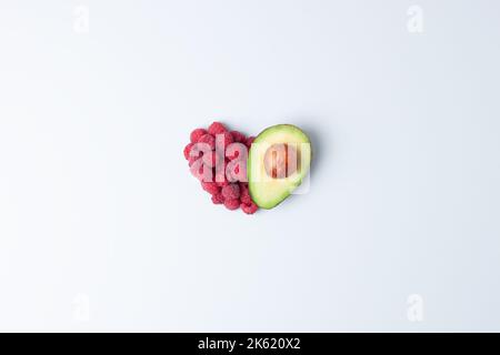 Concept été créatif. Forme de coeur faite de baies fraîches et d'avocat sur fond gris. Flat lay, espace de copie. Banque D'Images