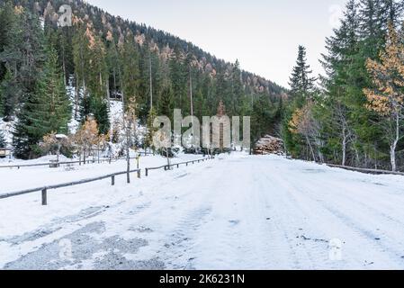 Parking vide et enneigé au pied de pistes boisées dans les montagnes en automne Banque D'Images