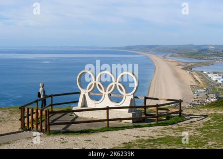 Fortuneswell, Portland, Dorset, Royaume-Uni. 11th octobre 2022. Météo Royaume-Uni. Un visiteur près des anneaux olympiques au point de vue de The Heights, au-dessus de Fortuneswell, sur l'île de Portland à Dorset, bénéficiant d'une vue spectaculaire sur la plage de Chesil et la côte jurassique pendant un après-midi ensoleillé et chaud. Crédit photo : Graham Hunt/Alamy Live News Banque D'Images