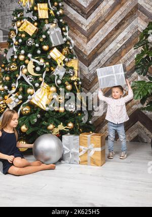Portrait de deux sœurs avec des cadeaux de Noël enveloppés le lendemain de Noël à côté d'un arbre de Noël décoré Banque D'Images