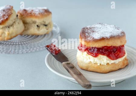 Un scone frais et traditionnel anglais fait maison. Le gâteau est fendu et rempli de confiture et recouvert de crème épaisse épaisse. Un délicieux thé à la crème Devon. Banque D'Images