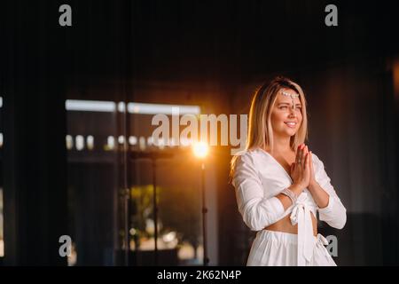 Portrait d'une fille souriante dans une robe blanche avec ses paumes clastées devant elle Banque D'Images