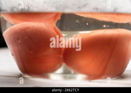 Éplucher les tomates dans de l'eau bouillante. Tomates dans un bol imbibé d'eau chaude. Banque D'Images