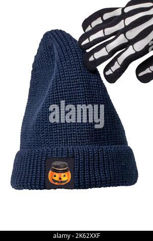 Équipement d'Halloween. Gros plan d'un bonnet ou d'une casquette tricoté bleu avec un autocollant citrouille et un gant squelette isolé sur blanc. Masque. Banque D'Images