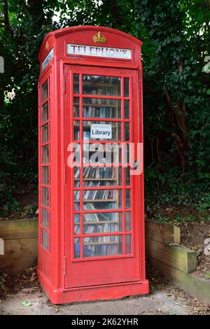 Ancienne boîte téléphonique classique britannique rouge pubienne repurposed comme bibliothèque de prêt gratuite remplie de livres Banque D'Images