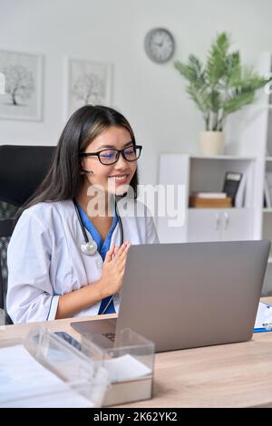 Bonne jeune femme asiatique médecin ayant en ligne la vidéo conférence avec le patient Banque D'Images