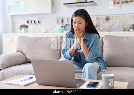 Femme asiatique nerveuse regardant l'écran d'ordinateur portable s'inquiétant de mauvaises nouvelles Banque D'Images