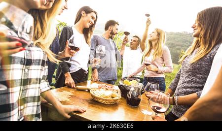 Amis milléniaux ayant du temps amusant à boire du vin rouge portes - heureux les gens de fantaisie appréciant la récolte à la ferme vignoble cave - jeunes amis conc Banque D'Images