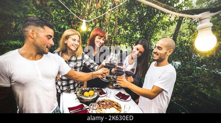 Des amis heureux ayant le plaisir de boire du vin rouge à la fête jardin arrière-cour - concept d'amitié des jeunes ensemble à la ferme maison vignoble domaine - Focus sur backg Banque D'Images