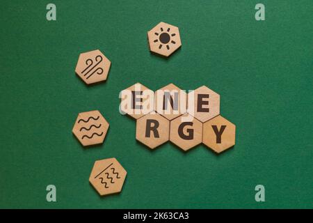 plaques de bois hexagonales avec le mot énergie et des icônes pour l'énergie solaire, éolienne, hydro et géothermique sur un fond vert Banque D'Images