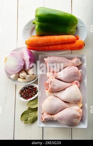 Des cuisses de poulet crues avec des légumes pour la cuisson sur la table de cuisine Banque D'Images