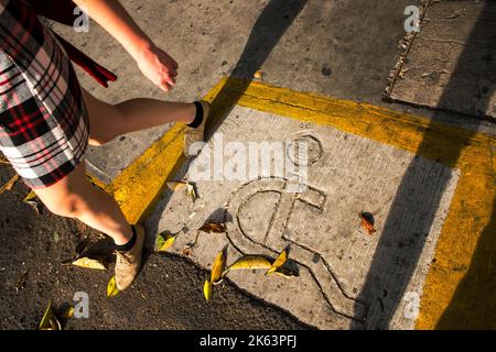 Signe de handicap avec un visage smiley, passage de rue, femme dans une jupe à carreaux Banque D'Images