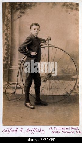 Une délicieuse carte de visite victorienne photo d'un jeune garçon debout fièrement à côté de son vélo Penny Farthing Banque D'Images