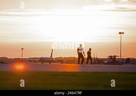 Deux aviateurs de l'aile de ravitaillement en carburant de 100th traversent la ligne de floightline en tant qu'avion KC-135 Stratotanker affecté à l'aile de ravitaillement en carburant de 121st, base de la Garde nationale de l'air de Rickenbacker, Ohio, taxis à Royal Air Force Mildenhall, Angleterre, le 3 octobre 2022. L’ARW de 100th appuie la mission de la Force aérienne dans le monde en élargissant la portée des avions de la Force aérienne des États-Unis. (É.-U. Photo de la Force aérienne par Tech. Sgt. Anthony Hetlage) Banque D'Images