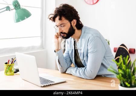 Jeune homme d'affaires concentré travaillant sur un ordinateur portable au bureau à domicile Banque D'Images